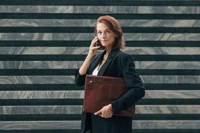 Young woman standing against corrugated iron