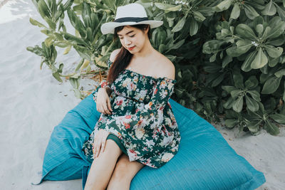 Smiling woman wearing hat sitting at beach