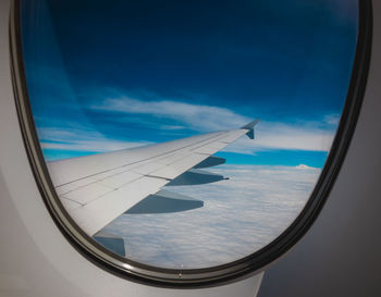 Aerial view of airplane wing over clouds seen through window