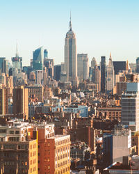 Empire state building in city against clear sky