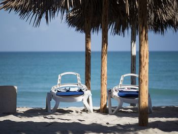 Deck chairs on beach against clear sky