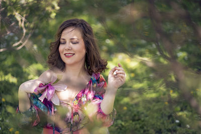 Portrait of young woman standing against plants