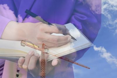 Double exposure image of man writing in book with crane