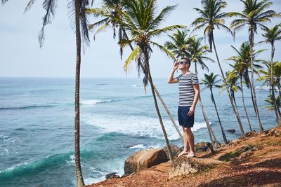 Mid adult man standing on cliff by sea against sky