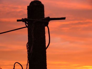 Low angle view of silhouette cross against sky during sunset