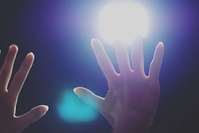 Close-up of hands against illuminated light