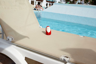 Lounge chair by swimming pool on sunny day