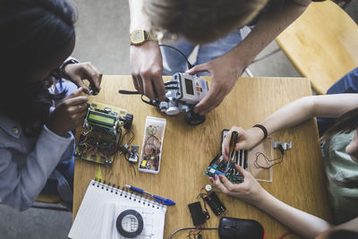 High angle view of multi-ethnic students preparing science project at desk in high school classroom