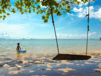 Rear view of woman on beach against sky