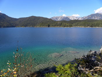 Scenic view of lake and mountains against blue sky