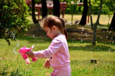 Side view of girl playing with bird on grass