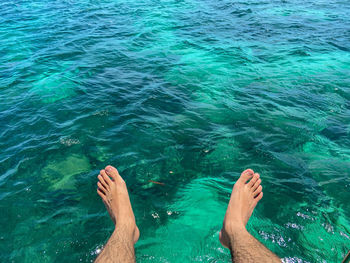 Low section of person relaxing in swimming pool