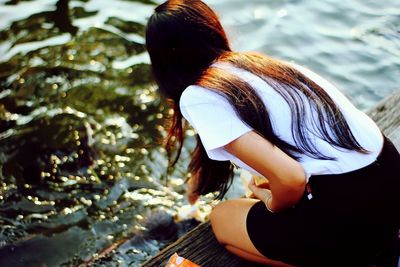 Rear view of woman bending on pier by river