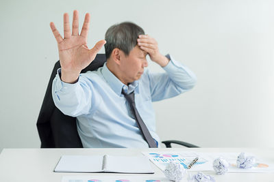 Businessman with headache showing stop gesture in office