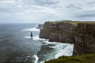 Scenic view of sea by cliff against sky