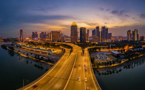 High angle view of illuminated street amidst buildings against sky