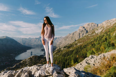 Woman standing on rock against sky