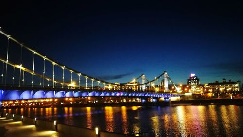 Illuminated bridge over river at night