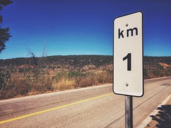 Information sign on road against clear blue sky