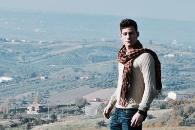 Portrait of smiling young man standing on hill against landscape