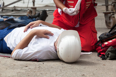 Paramedic performing cpr on person lying on street