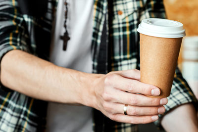 Midsection of man holding coffee cup