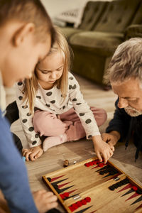 Girl learning backgammon with grandfather at home