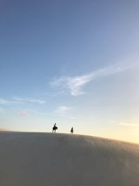 Silhouette people walking on desert against sky