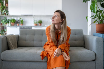 Young woman using laptop while sitting on sofa at home