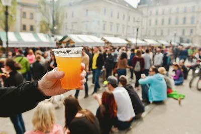 Close-up of person holding beer in disposable glass