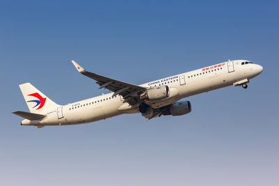 Low angle view of airplane flying against clear blue sky