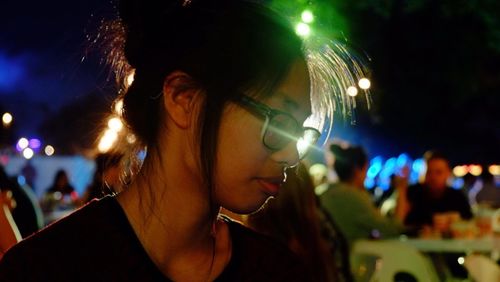 Close-up of young woman looking away at night