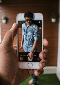 Cropped hand with picture of man on mobile phone