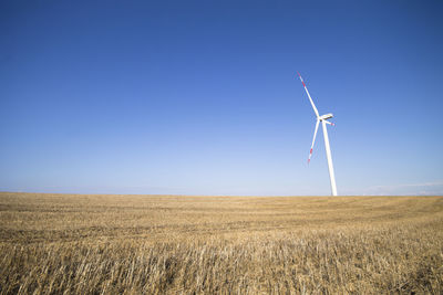 Wind turbines on field against clear sky