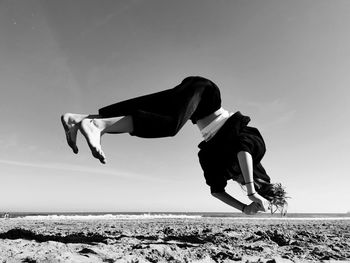 Full length of girl jumping against sky