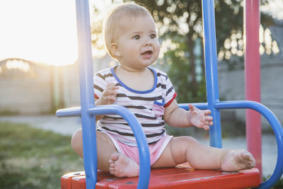 Portrait of cute boy sitting on slide at playground