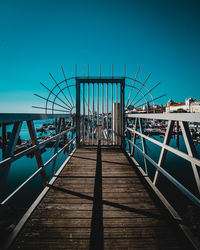 Pier over sea against clear blue sky