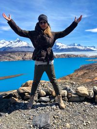 Full length of woman with arms outstretched standing against sky