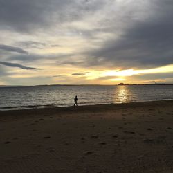 Silhouette person on beach against sky during sunset