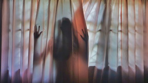 Close-up of woman's hands behind curtain