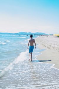 Man walking on beach against clear sky