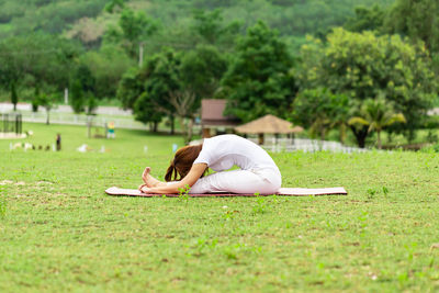 Full length of woman doing yoga on grass 