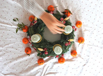 Cropped image of woman decorating christmas wreath on table