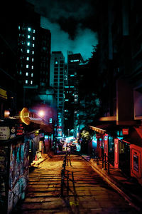 Illuminated city street against sky at night