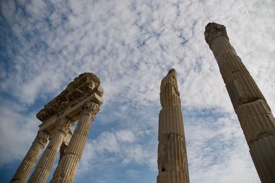 Low angle view of historical columns against cloudy sky