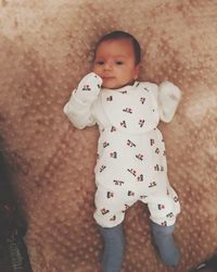 High angle view of cute baby girl standing on bed at home