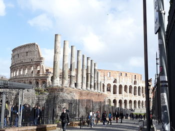 People at historical building against sky