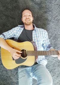 Portrait of man playing guitar against wall