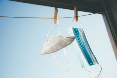 Low angle view of clothes hanging on rope against clear blue sky