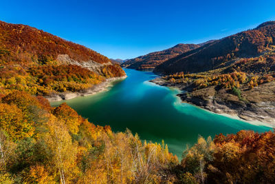 Scenic view of lake and mountains against clear blue sky